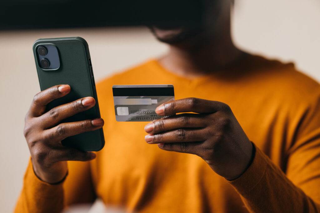 Black woman shopping online with credit card and smartphone, secure payment concept